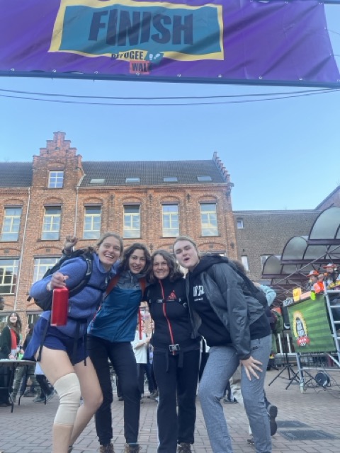 Vier wandelaars poseren onder de finishboog van de Refugee Walk